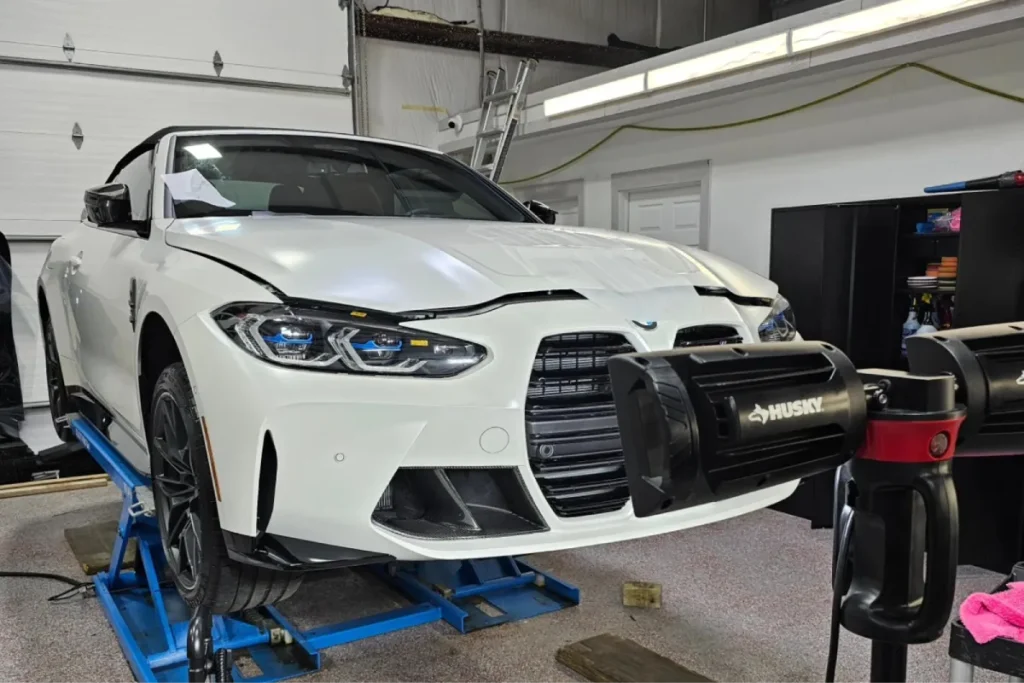 White BMW receiving ceramic coating in auto detailing garage.